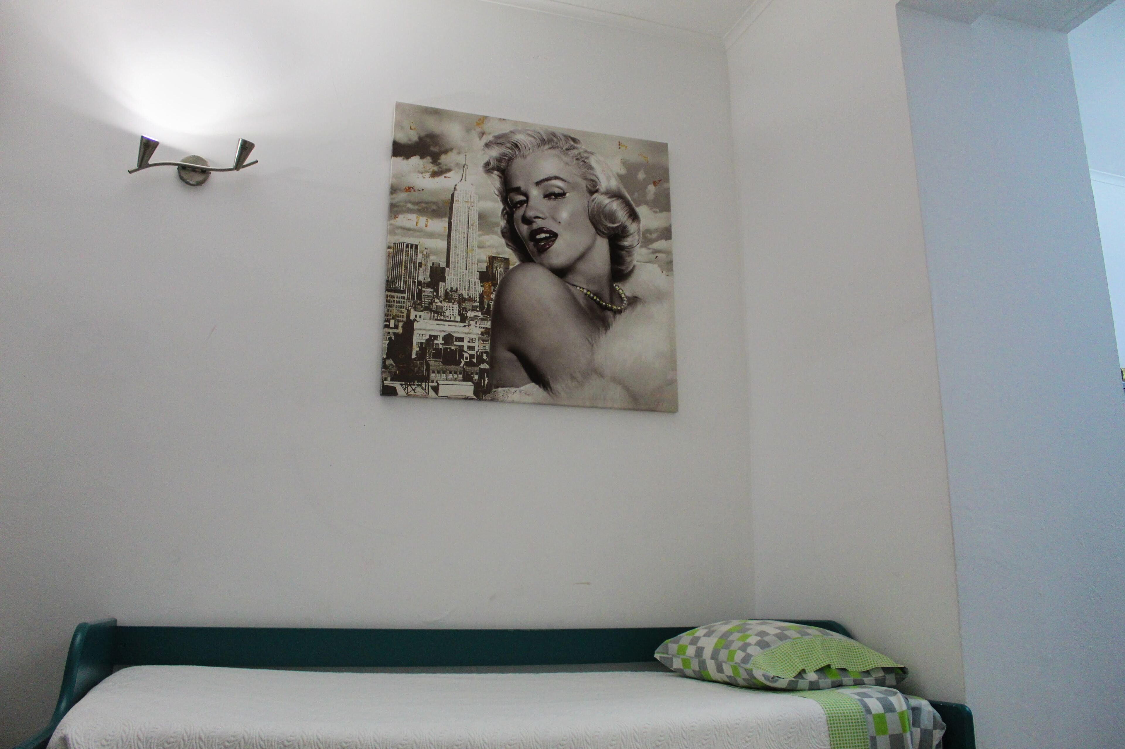 A bedroom with a bed, a pillow, and a wall-mounted light fixture.
