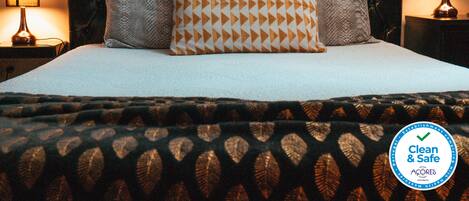 A neatly made bed with a patterned bedspread, two pillows, and a dark upholstered headboard.