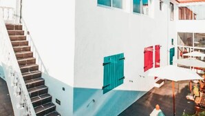 A white building with a red-tiled roof, a staircase, and a sign indicating 'Clean & Safe'. - Vintage Place - Azorean Guest House (Ponta Delgada)