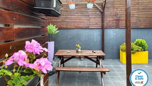 A patio with a wooden table and benches, surrounded by potted plants and flowers. - Vintage Place - Azorean Guest House (Ponta Delgada)