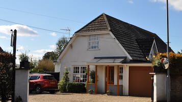 A single-story house with a sloped roof, a garage door, and a small porch area with potted plants.