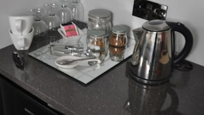 A kitchen counter with various kitchen utensils, a kettle, and glass containers. - Canford Crossing (Wimborne)