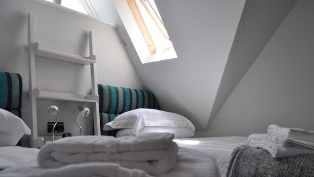 A bedroom with a bunk bed, a desk with a chair, a window, and a bed with a blanket and pillows. - Canford Crossing (Wimborne)