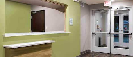 A reception area with a green wall, a wooden counter, and a glass door entrance.