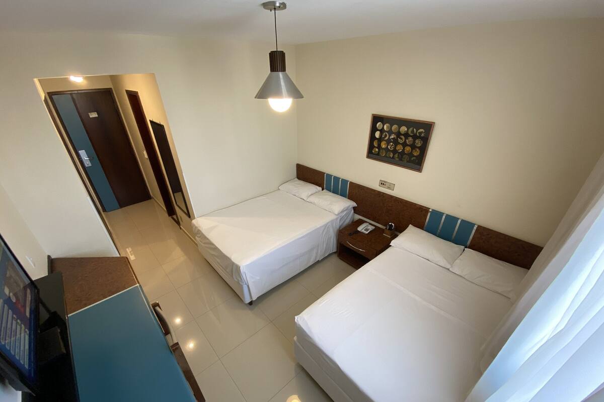 Habitación de hotel con dos camas, un escritorio, un teléfono y un cuadro colgado en la pared.