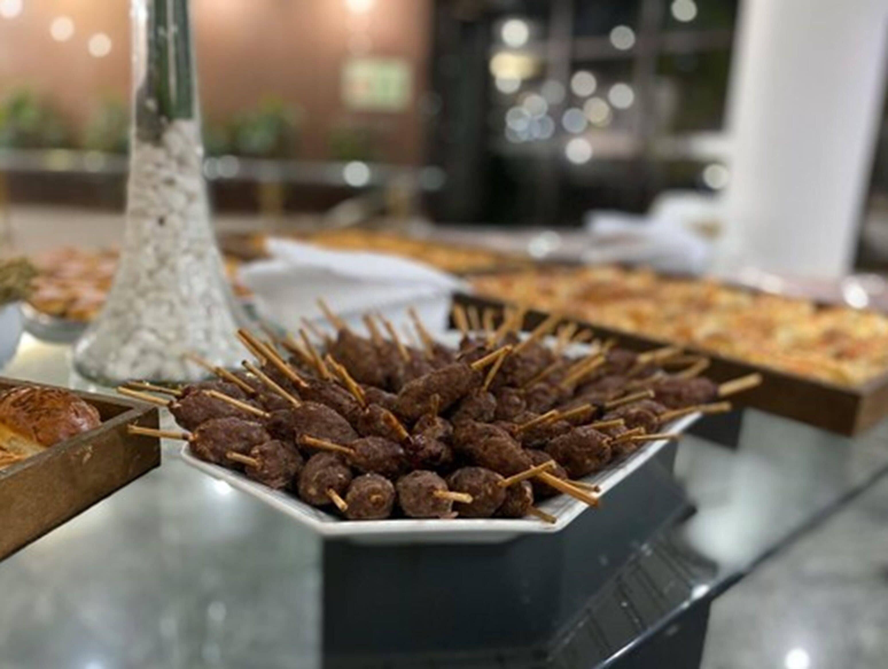 A buffet table with skewered meatballs and other dishes.