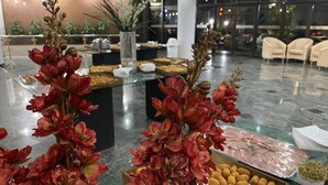 A buffet setup with various food items and decorative floral arrangements. - Sumatra Hotel e Centro de Convenções (Londrina)