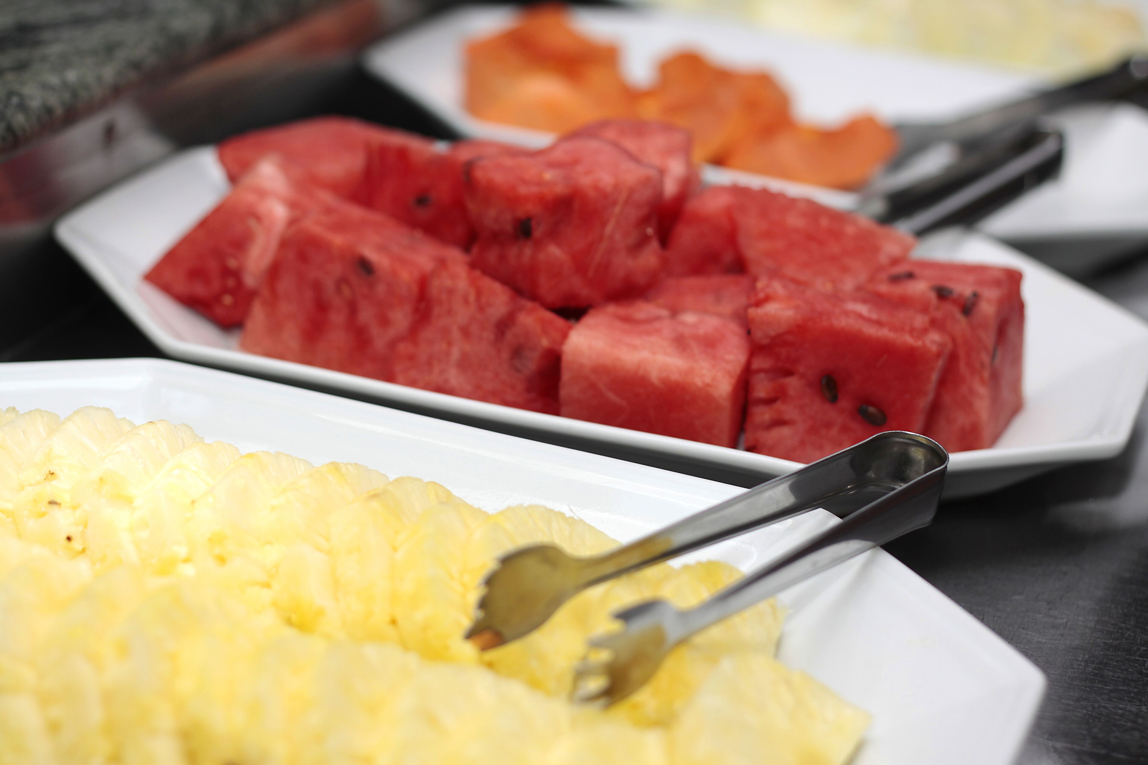 A buffet with watermelon and pineapple slices.