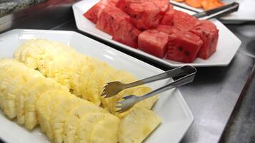 Une table de buffet avec des assiettes remplies de tranches d’ananas et de pastèque.