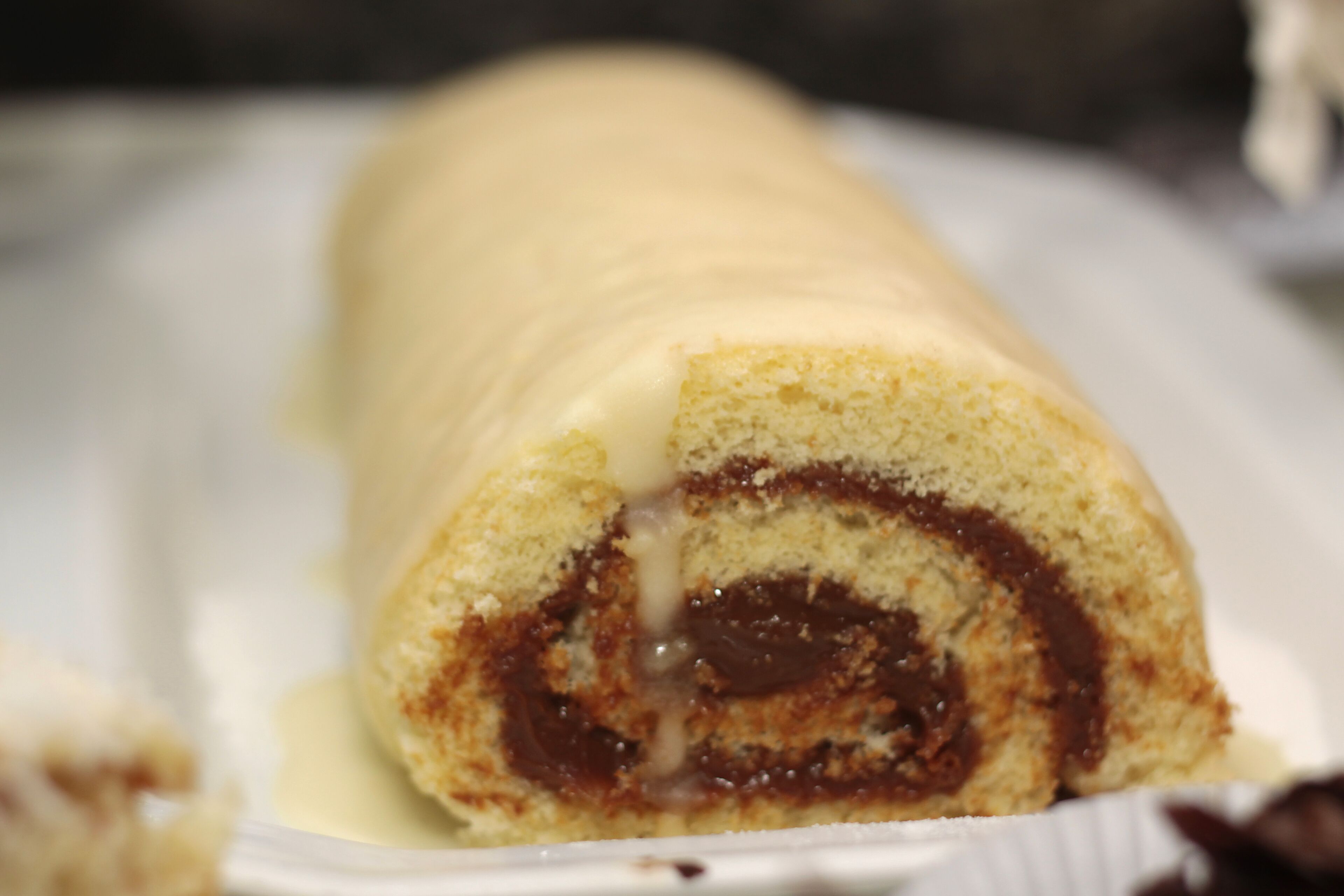 A rolled dessert with a chocolate filling, served on a white plate.
