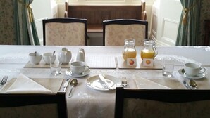A breakfast table set with white dishes, tea cups, and juice bottles, with a view of greenery outside. - Upper Letton Farmhouse (Bucknell)
