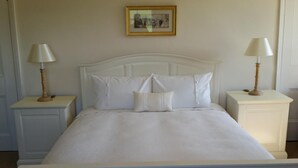 A neatly made bed with white linens and pillows, flanked by two bedside tables with lamps, in a room with a simple, clean design. - Upper Letton Farmhouse (Bucknell)