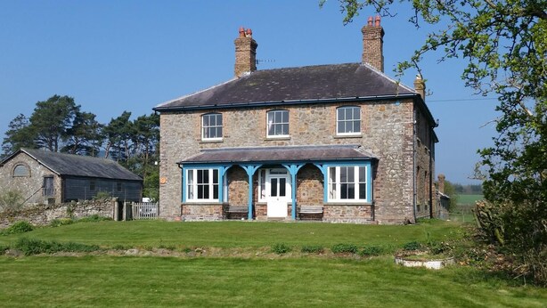 A two-story stone house with a front porch and a small attached shed. - Upper Letton Farmhouse (Bucknell)