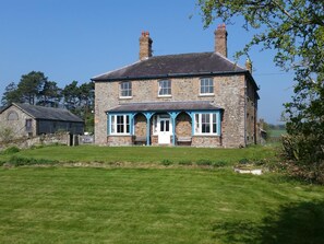 A two-story stone house with a front porch and a small attached shed. - Upper Letton Farmhouse (Bucknell)