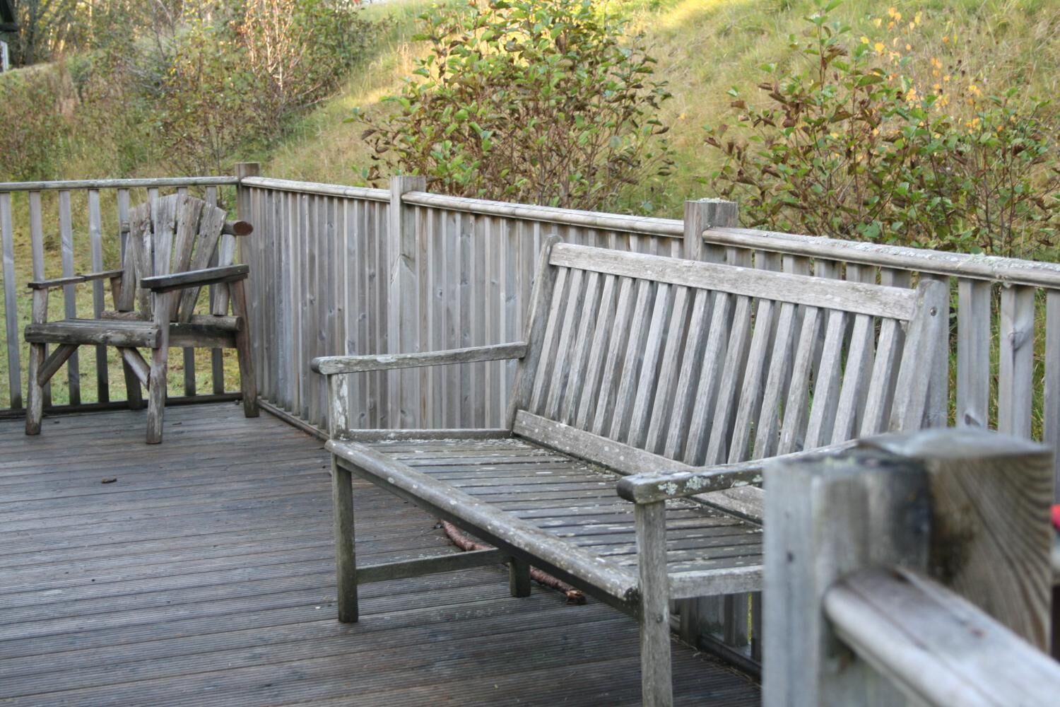 A wooden deck with a bench and a chair.