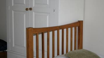 A wooden headboard with vertical slats, a white door with round knobs, and a green pillow on a bed.
