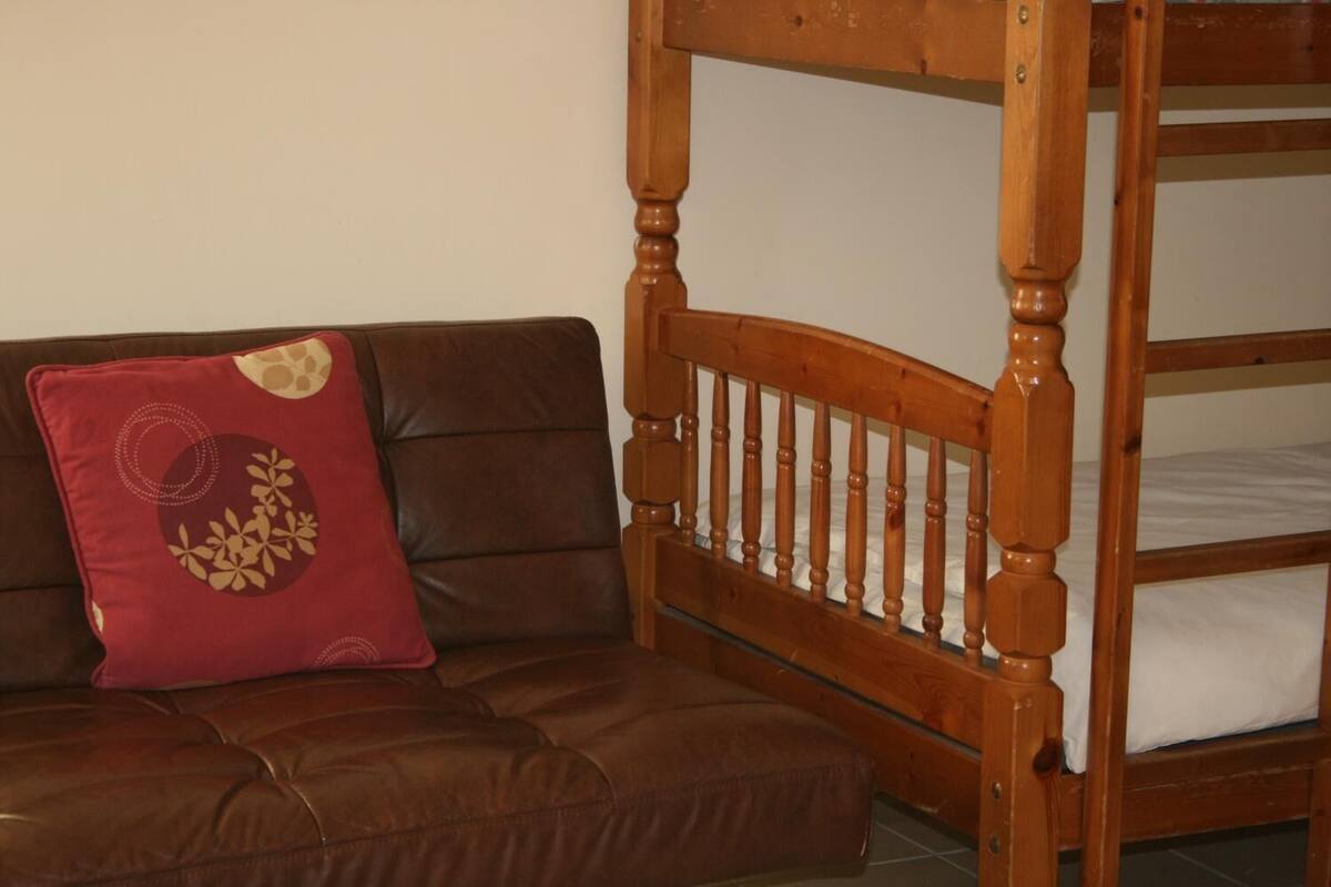 A brown leather sofa with a red pillow featuring a floral design.