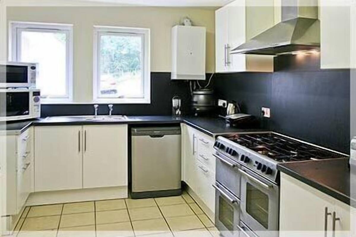 A kitchen with a stove, microwave, sink, and cabinets.