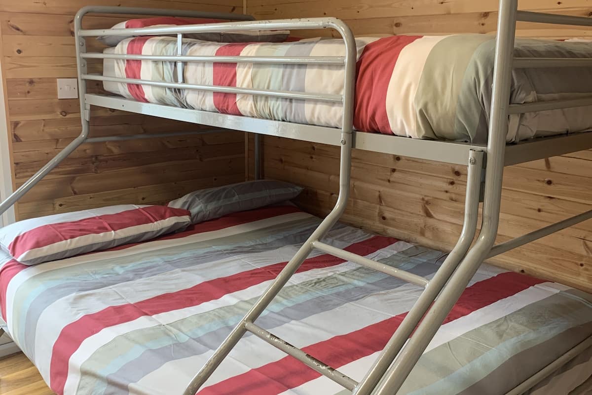 A bunk bed with a striped bedspread in a wooden room.