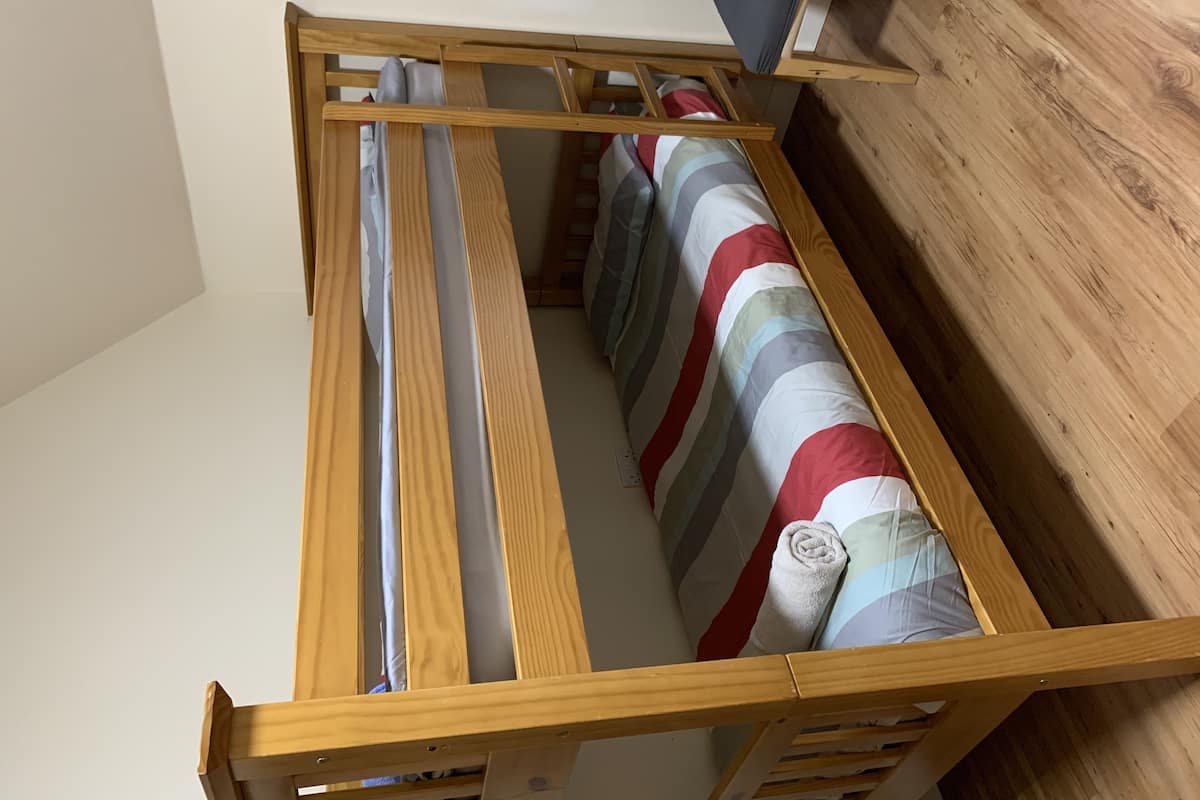 A wooden bed frame with a striped bedspread and pillows.