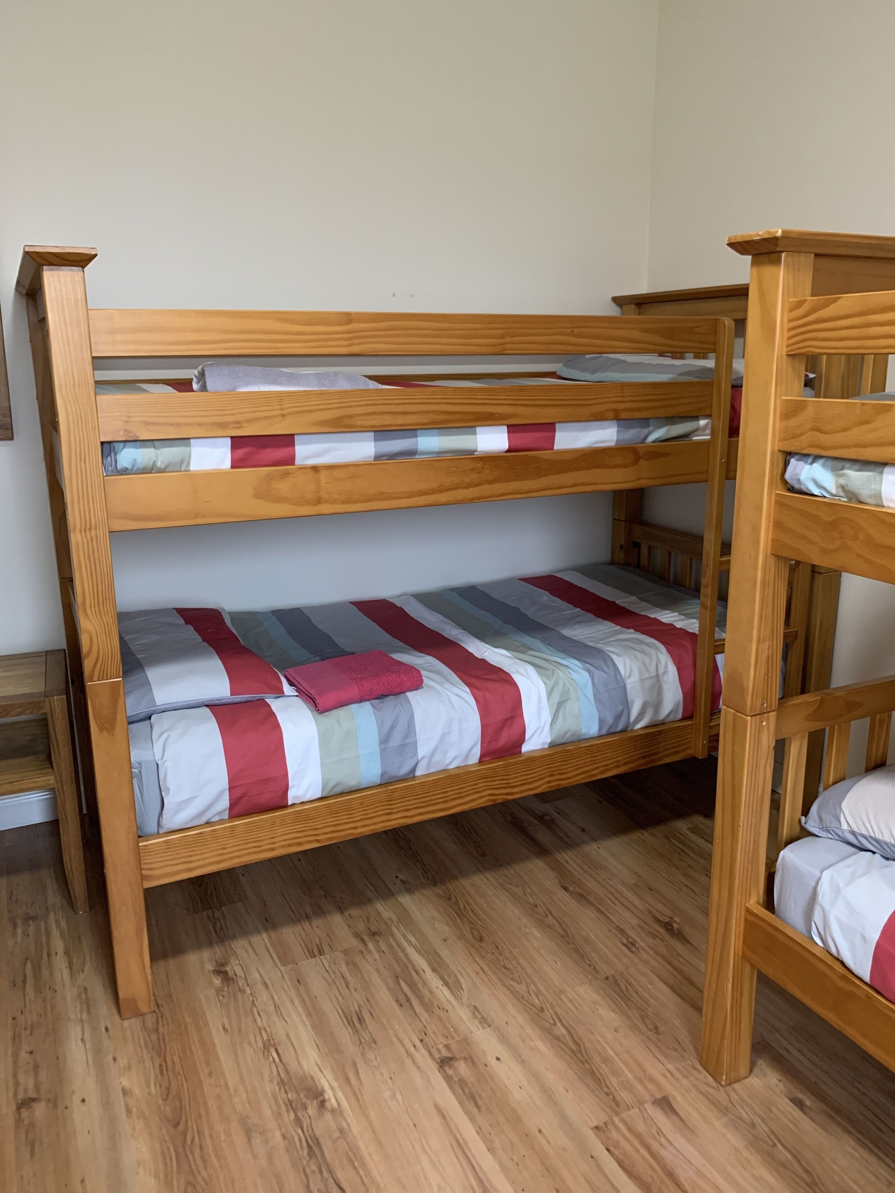 Un letto a castello con due piani, struttura in legno e biancheria a righe.