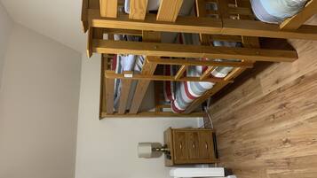 A room with a wooden bunk bed, a wooden cabinet, and a white bedside table.