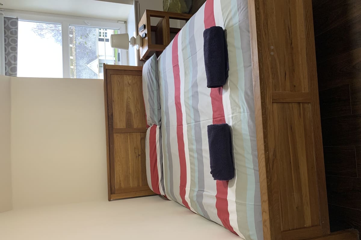 A room with a bed, wooden wardrobe, and a window.