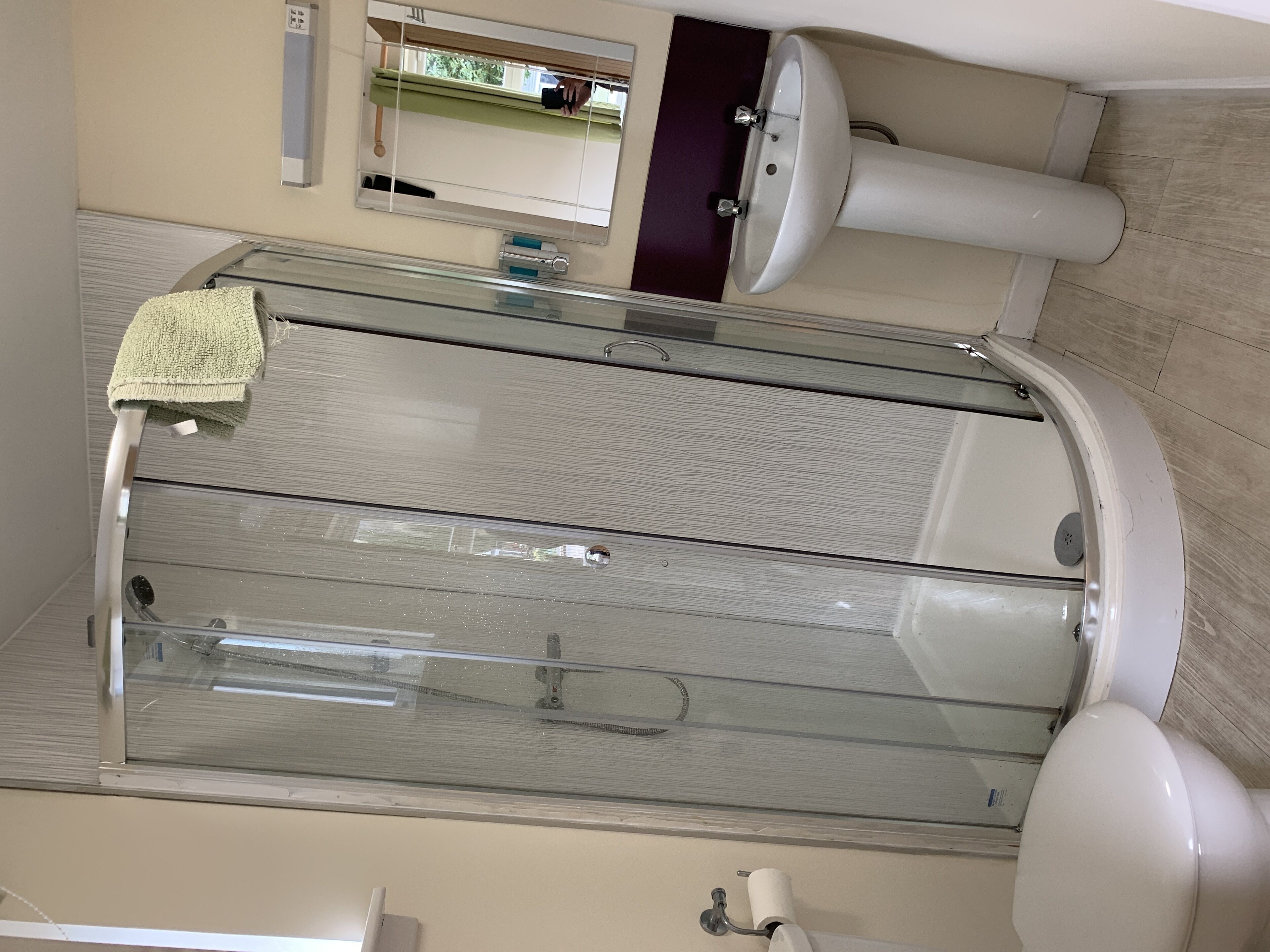 Un bagno moderno con cabina doccia in vetro, lavabo bianco e water.