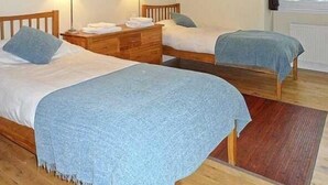 Habitación con dos camas individuales, cabeceros de madera, mesitas de noche con lámparas y vistas al exterior a través de una ventana.