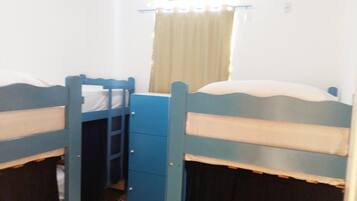 Quarto em dormitório com duas beliches, uma cômoda pequena e um aparelho de ar condicionado.
