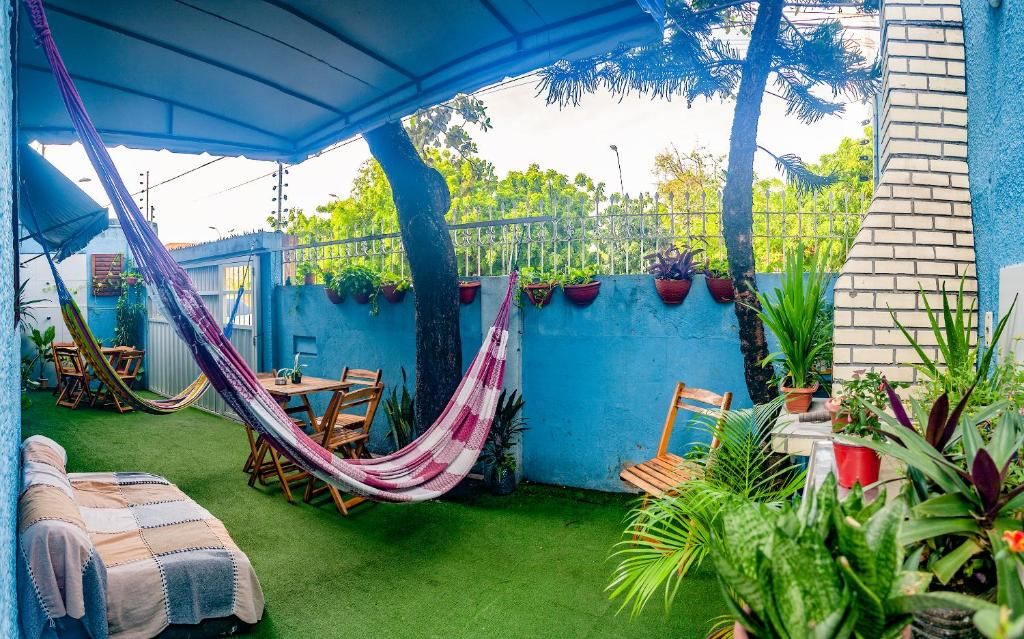 Un patio techado con una hamaca, una mesa de madera y sillas.