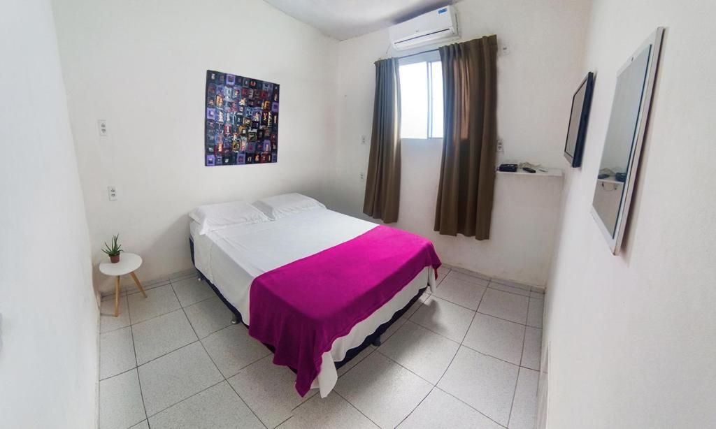 Un dormitorio con una cama, una mesita con una planta, un cartel en la pared y un equipo de aire acondicionado.
