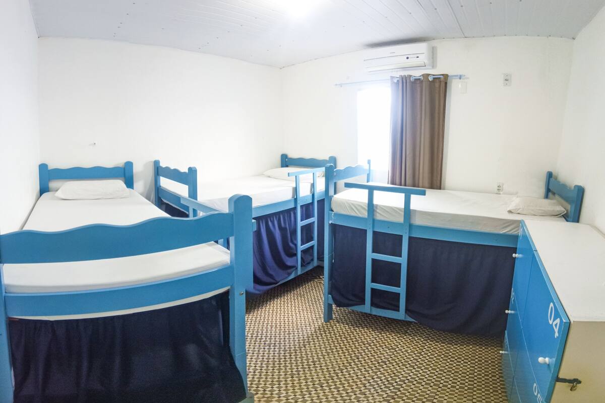 Ein Schlafsaalzimmer mit Etagenbetten, einem gemusterten Boden und einer Klimaanlage an der Wand.