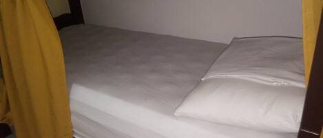 A single bed with white bedding and a wooden headboard.
