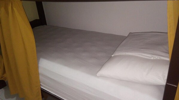 Una cama individual con ropa de cama blanca y cabecera de madera.