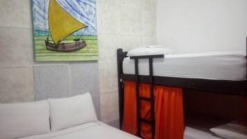 Una cama litera con colchón y almohadas, un cuadro de un velero en la pared y una pared con azulejos.