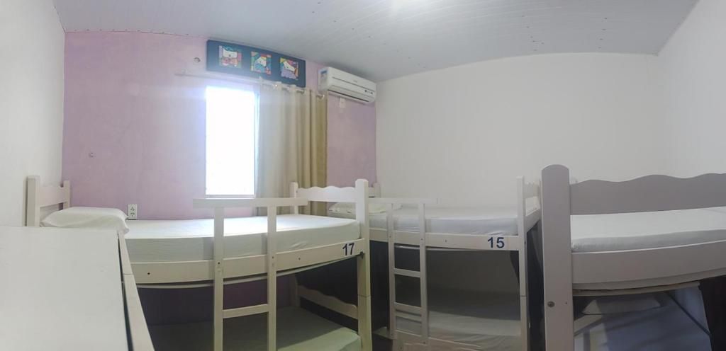 Un dormitorio con literas numeradas 15 y 17, una ventana con cortinas y un equipo de aire acondicionado.