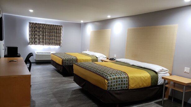 Une chambre d’hôtel avec deux lits, un bureau et une chaise.