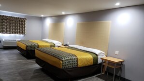 Une chambre d’hôtel avec deux lits, une petite table et un climatiseur fixé au mur.