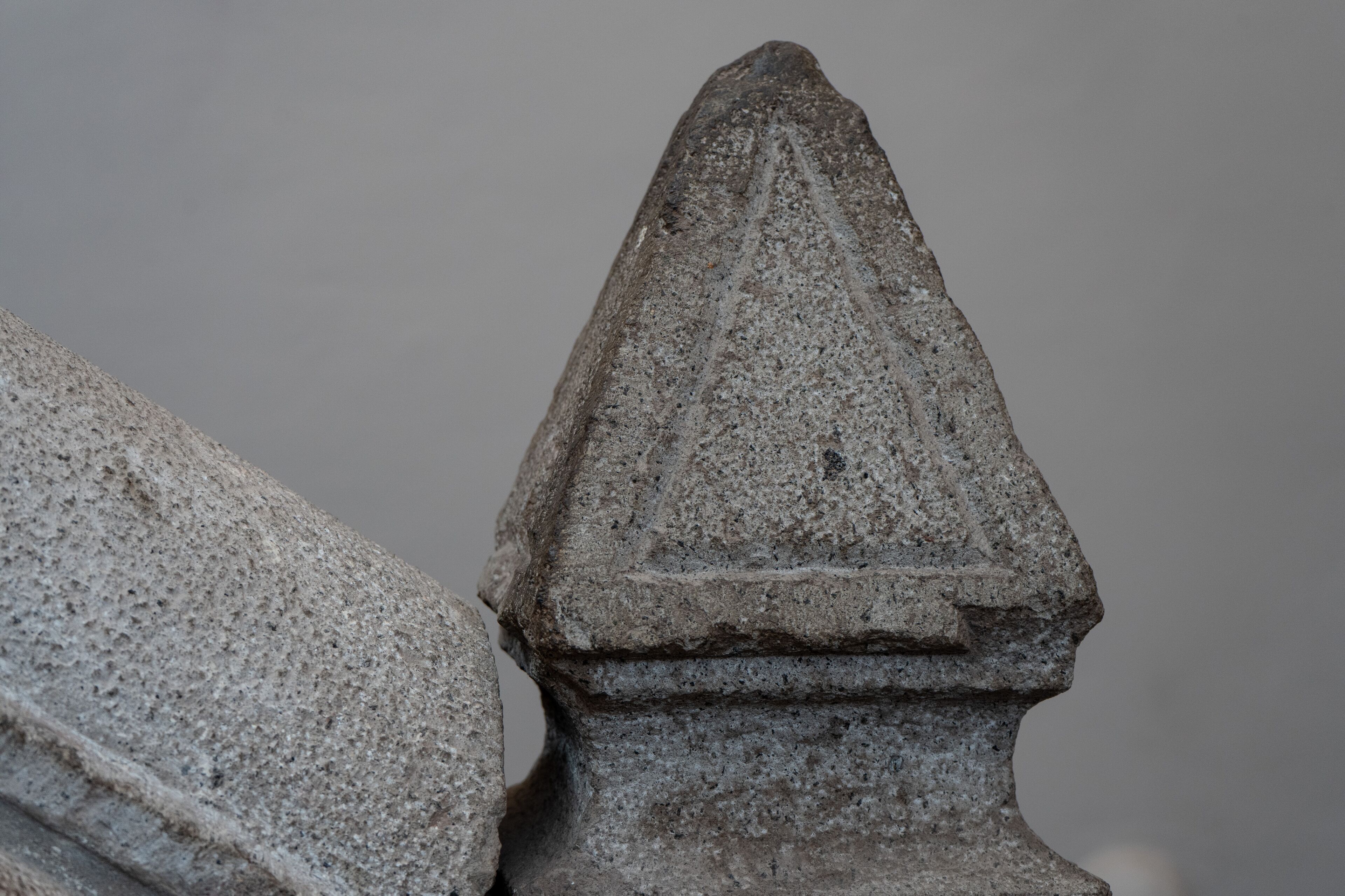 A close-up of a stone structure with a pointed top and a base with horizontal layers.