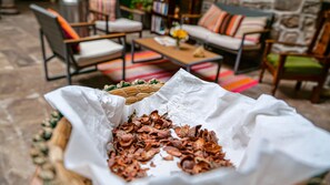 A cozy outdoor seating area with a wicker basket and a paper bag filled with dried leaves. - La Casona Real (Cusco)
