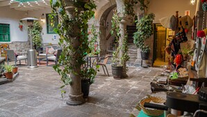 A courtyard with stone flooring, potted plants, outdoor seating, and a staircase leading to an upper level. - La Casona Real (Cusco)