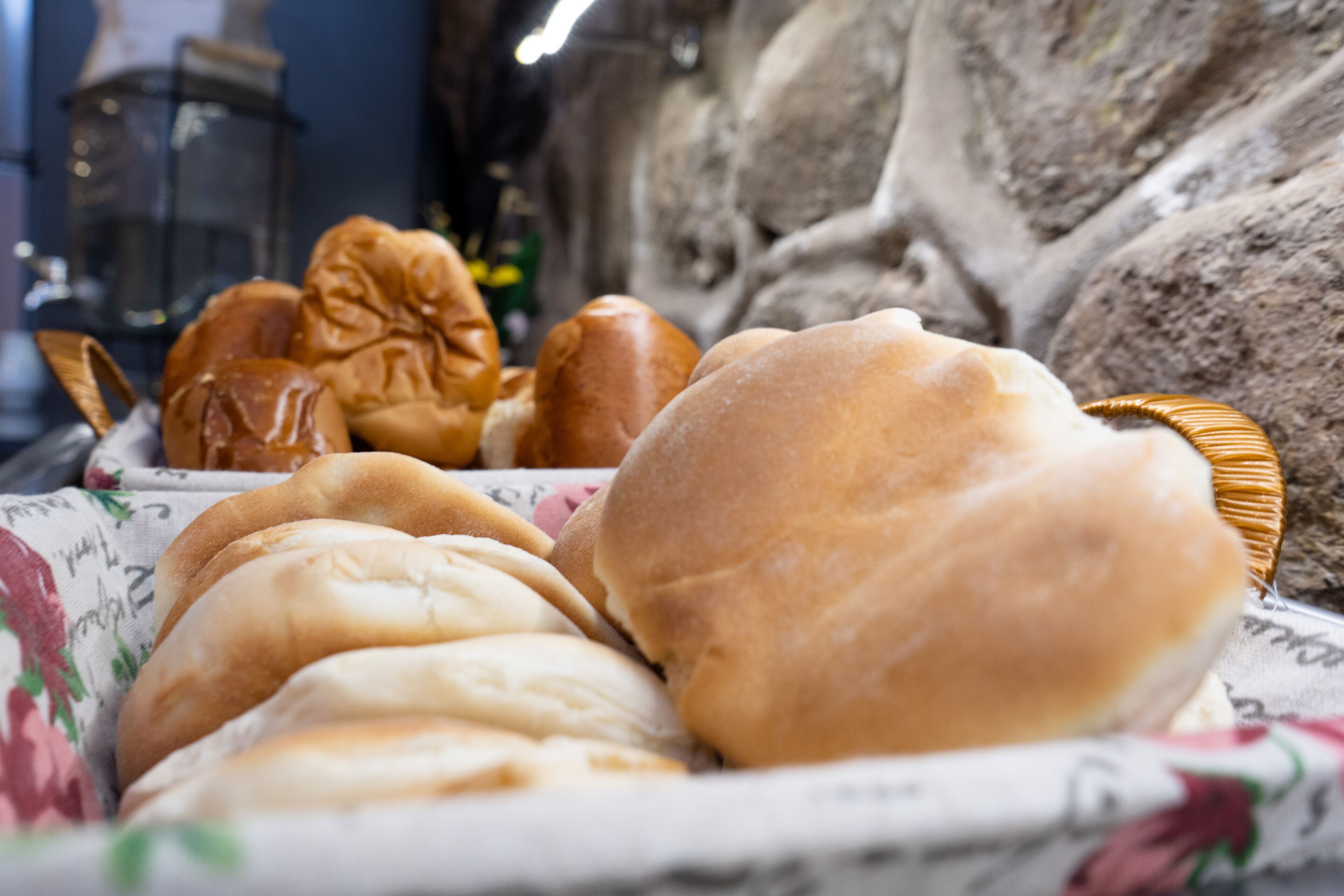 A selection of bread rolls on a table with a floral cloth.