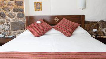 Una cama bien tendida con dos almohadas a rayas y un cabecero decorativo.