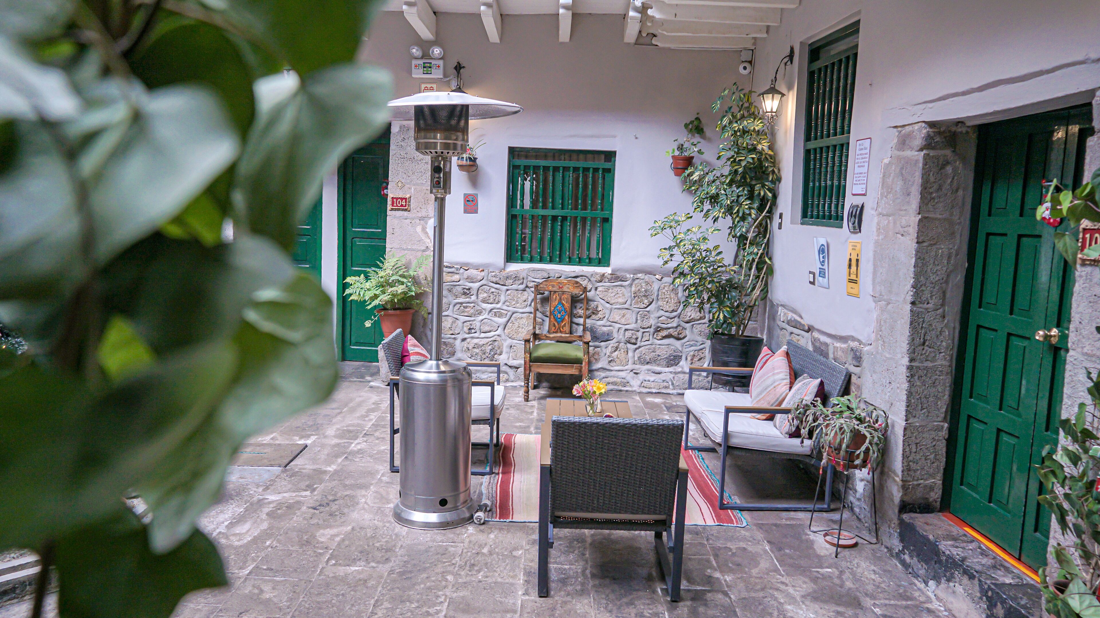 A courtyard with stone walls, green doors, and potted plants.