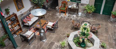 A courtyard with a seating area, a bookshelf, a table with a kettle, and a water feature.
