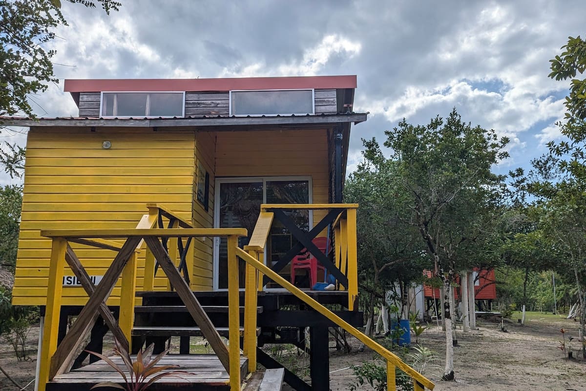 Un bâtiment jaune avec un toit rouge, un escalier et un petit porche.