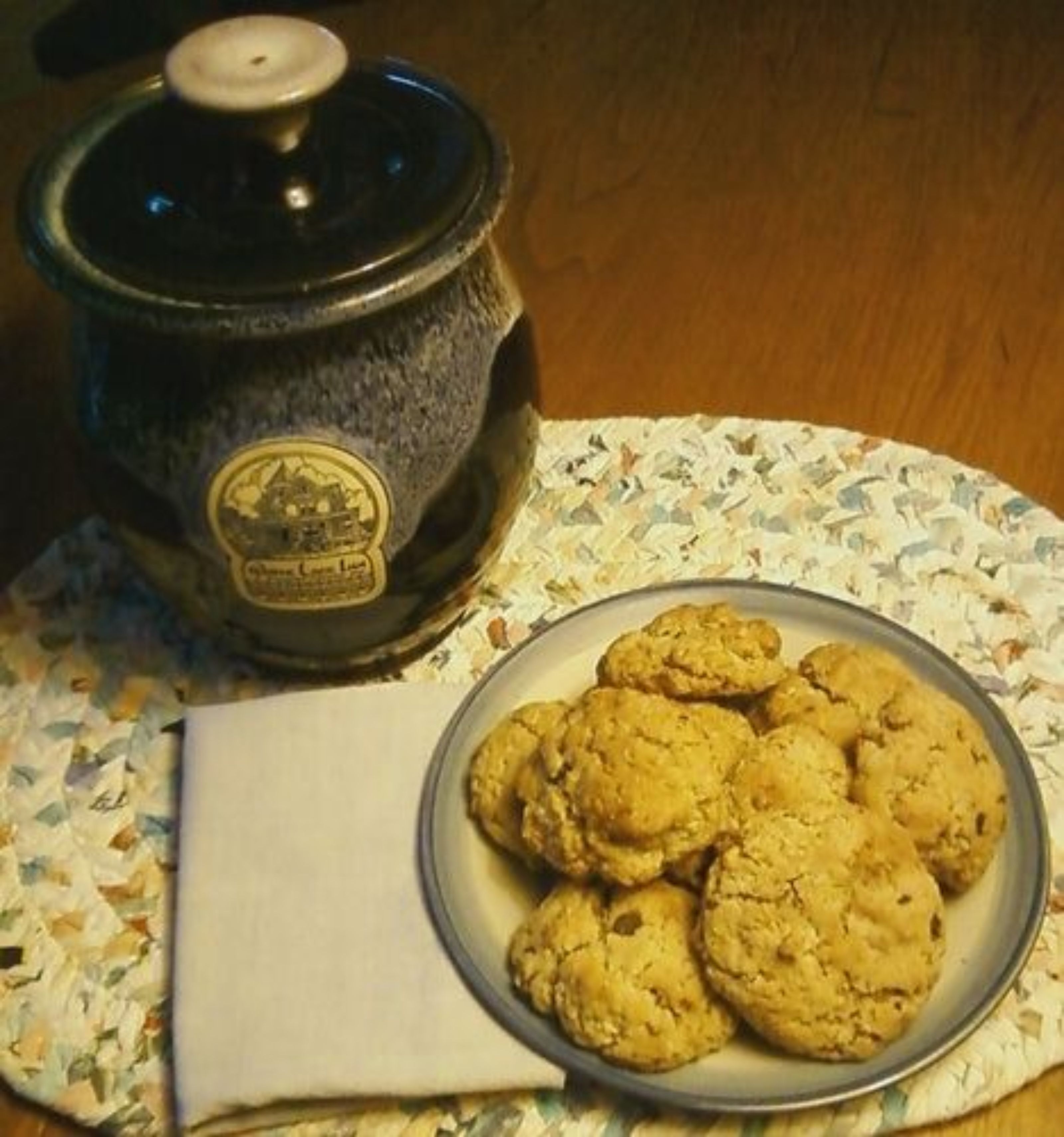 A kitchen with a slow cooker and a plate of cookies on a table.