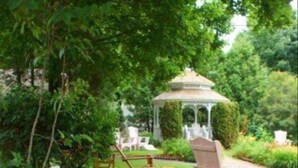 A garden with a gazebo, a sign for White Lace Inn, and outdoor seating. - White Lace Inn (Sturgeon Bay)