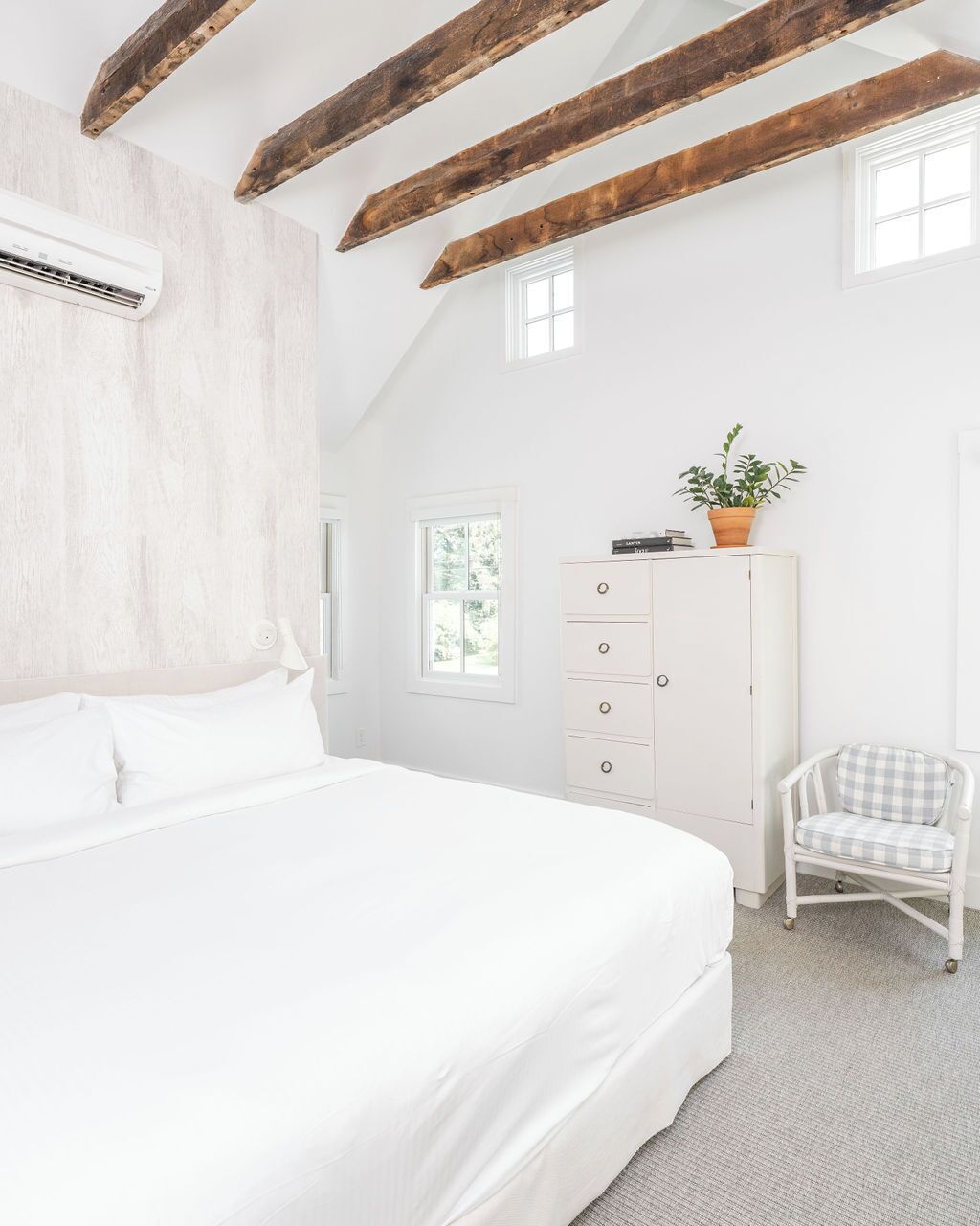 A bedroom with a large bed, a dresser, a chair, and a window.